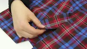 Garn fixieren: An der Position des alten Einstichloches die Nadel an der Innenseite ansetzen und den Faden durchziehen. Auf der Außenseite neben dem Einstichloch wieder zurückstechen. Im Anschluss Nadel durch die Garnschlaufe ziehen und den Faden fixieren.