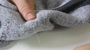 Wenn das Loch ausreichend geschlossen ist, kann der Faden vernäht werden. Dazu mehrmals den Faden an der gleichen Stelle des Oberstoffes durchstechen. Anschließend den übrigen Faden abschneiden.