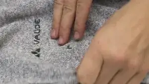 Das Oberteil auf die linke Seite wenden. Mit der Nadel an einem Anfangspunkt einstechen, am besten am oberen Lochbereich. Den Faden durchziehen, bis nur noch ca. 5 cm überstehen. Vor dem Einstechen auf der anderen Lochseite seitlich vorhandene Maschen (welche überstehen) aufnehmen, damit sich keine weiteren Maschen löschen.