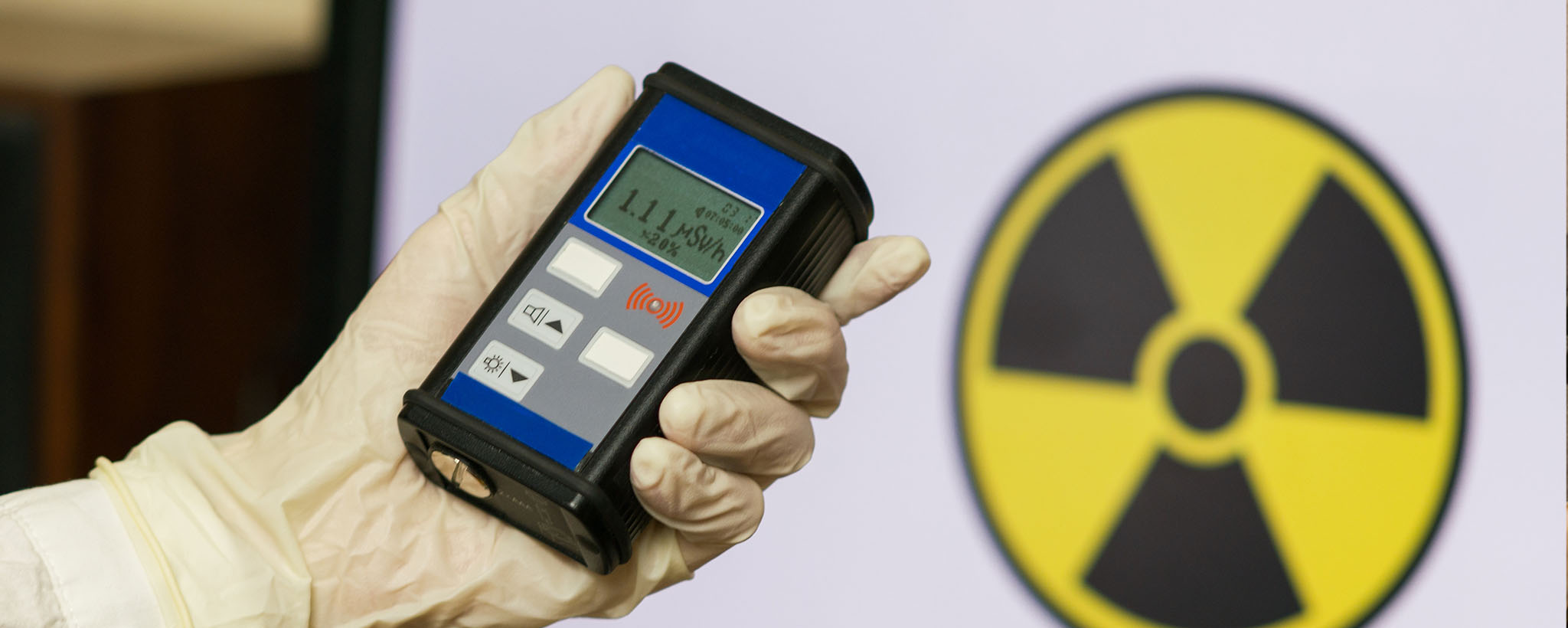 A hand holding a Geiger counter measuring radiation exposure